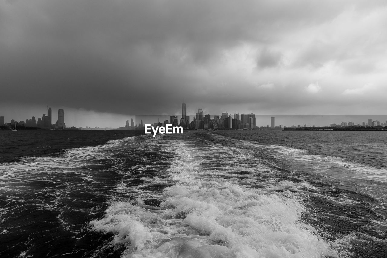 SEA BY CITY BUILDINGS AGAINST SKY