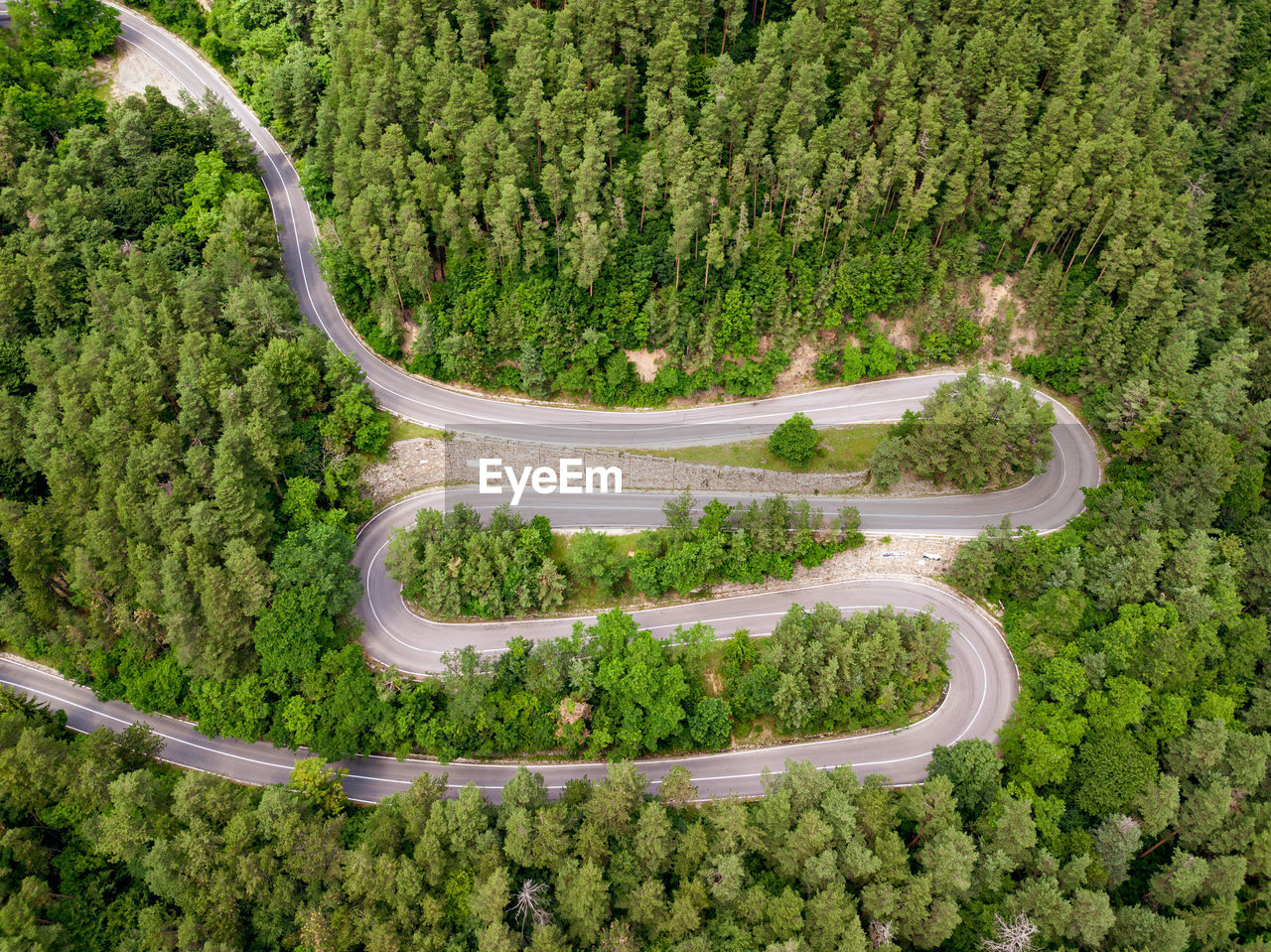 Winding road through the forest, from high mountain pass, in summer time. aerial view by drone