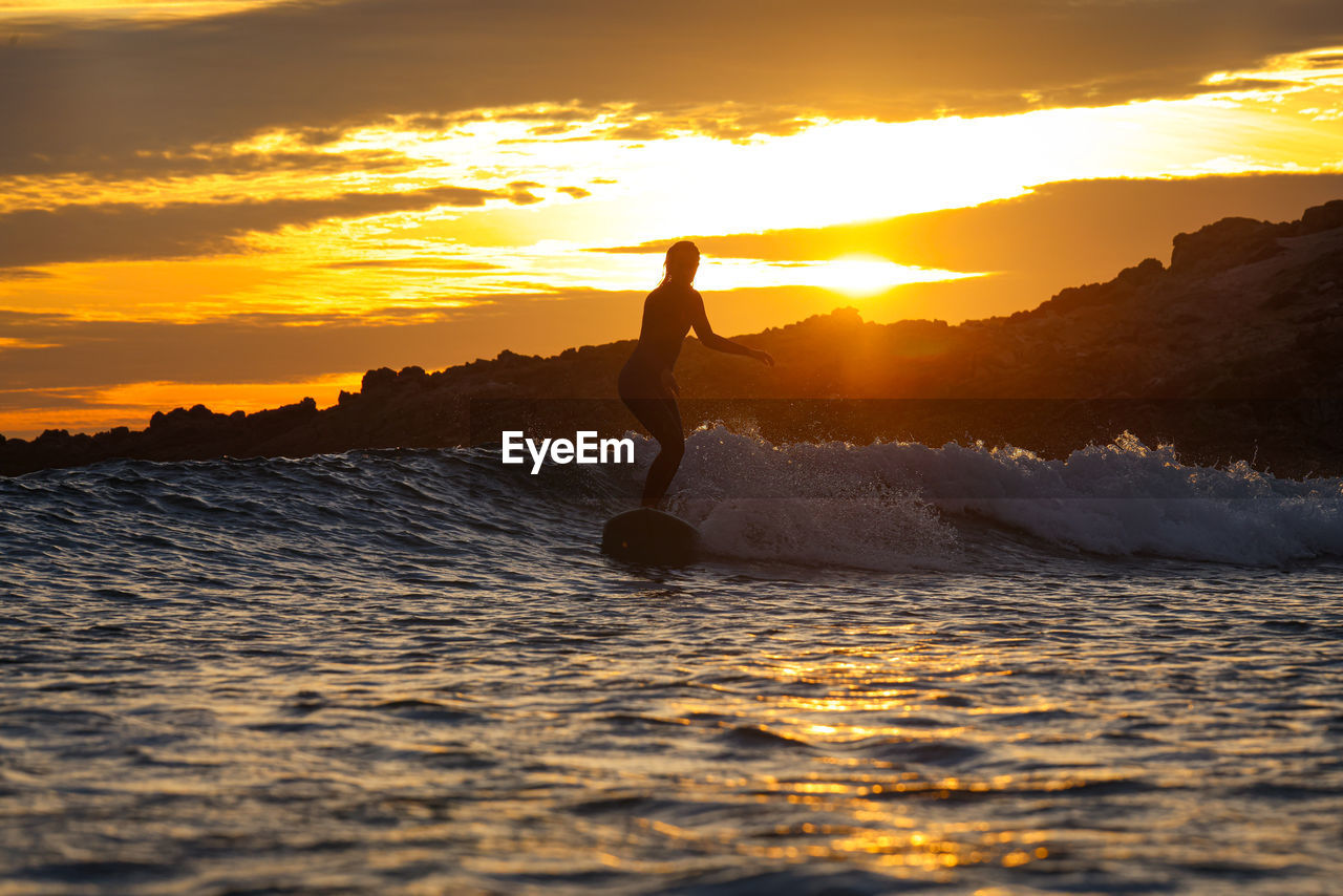 side view of man jumping at sunset