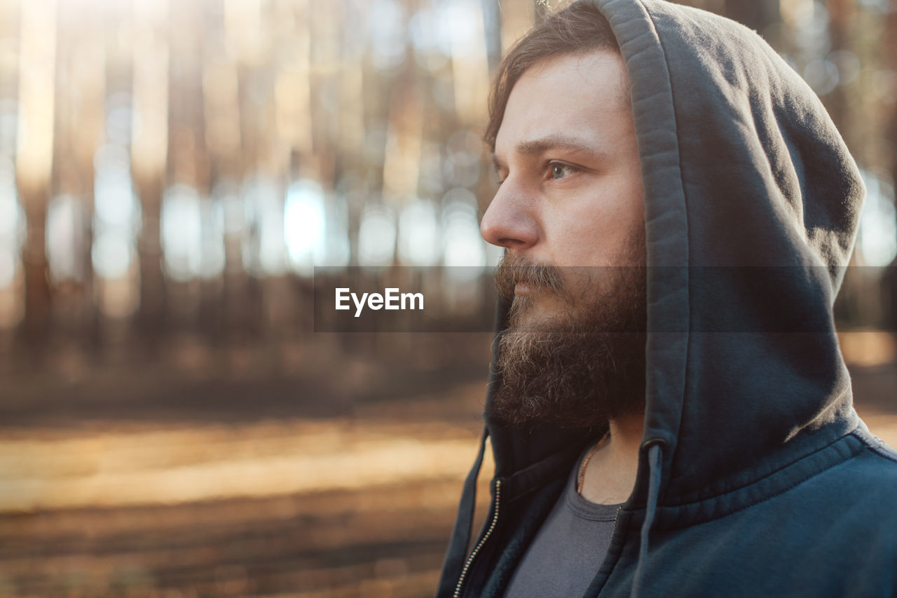 Bearded man in hooded jacket looking away