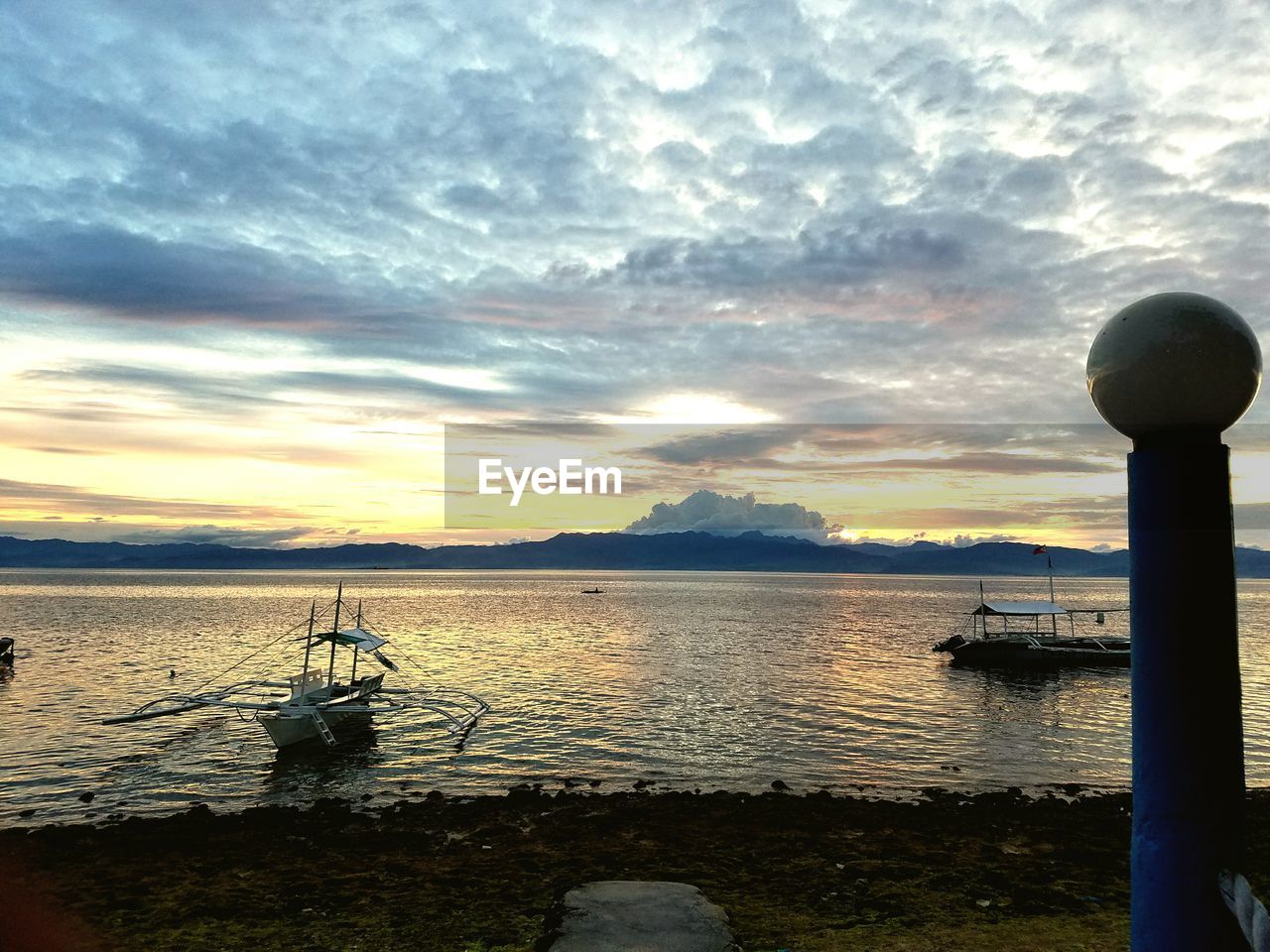 Scenic view of sea against cloudy sky at sunset