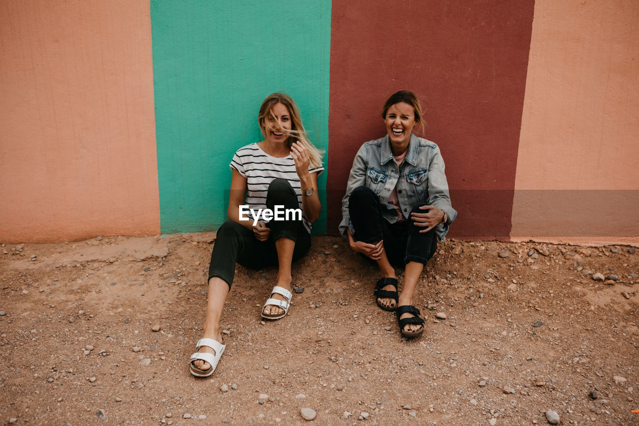 Friends sitting against wall