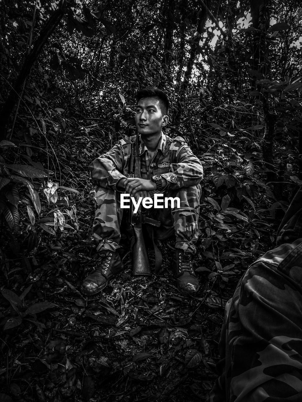 Thoughtful male army officer sitting in forest