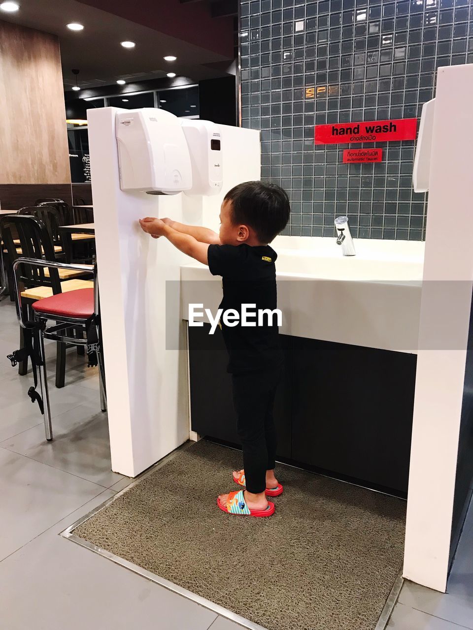 Side view of boy drying hands at restaurant