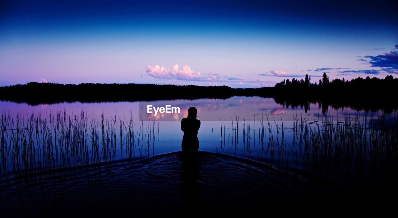 Rear view of woman overlooking calm lake