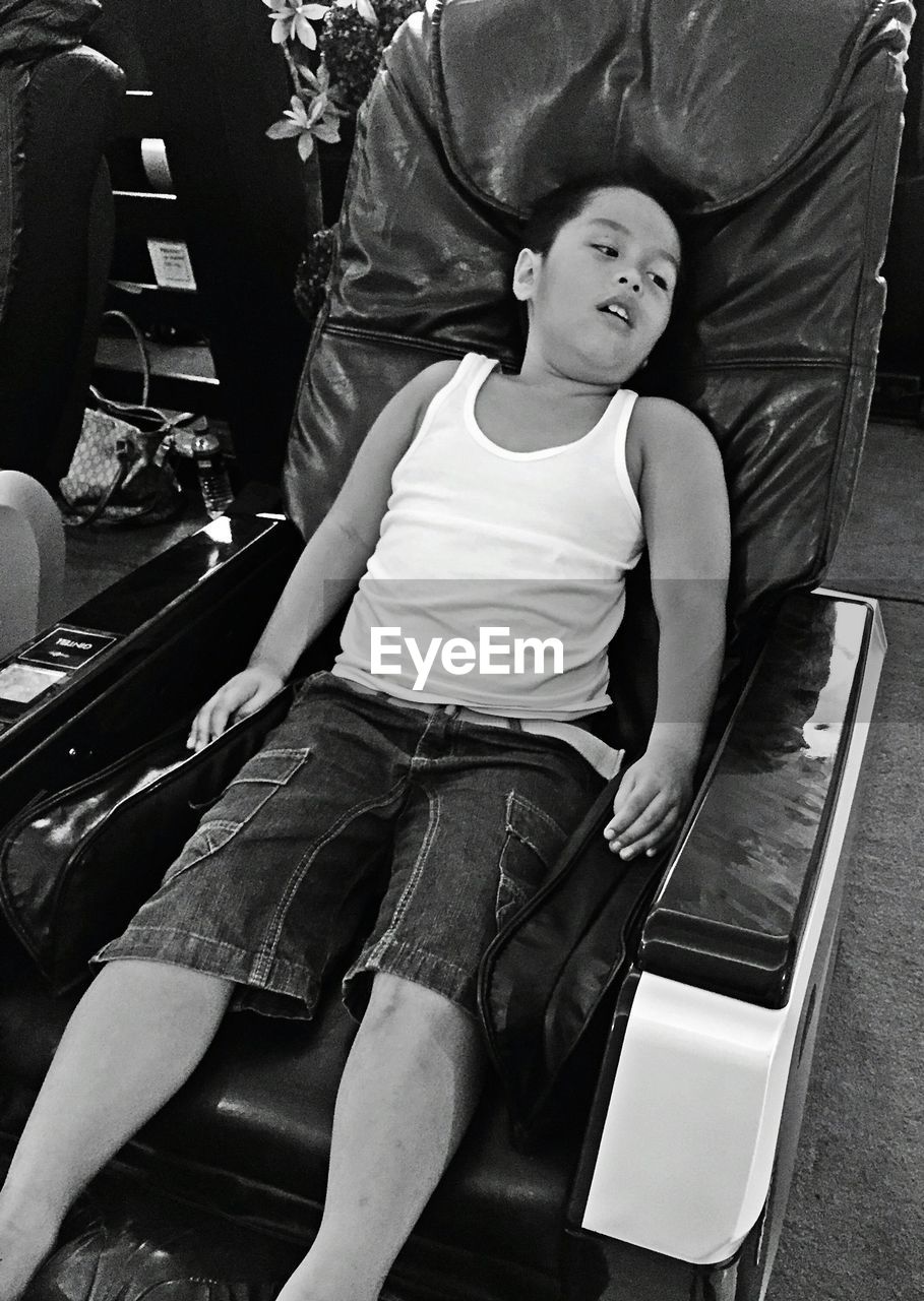 High angle view of boy resting on massage chair