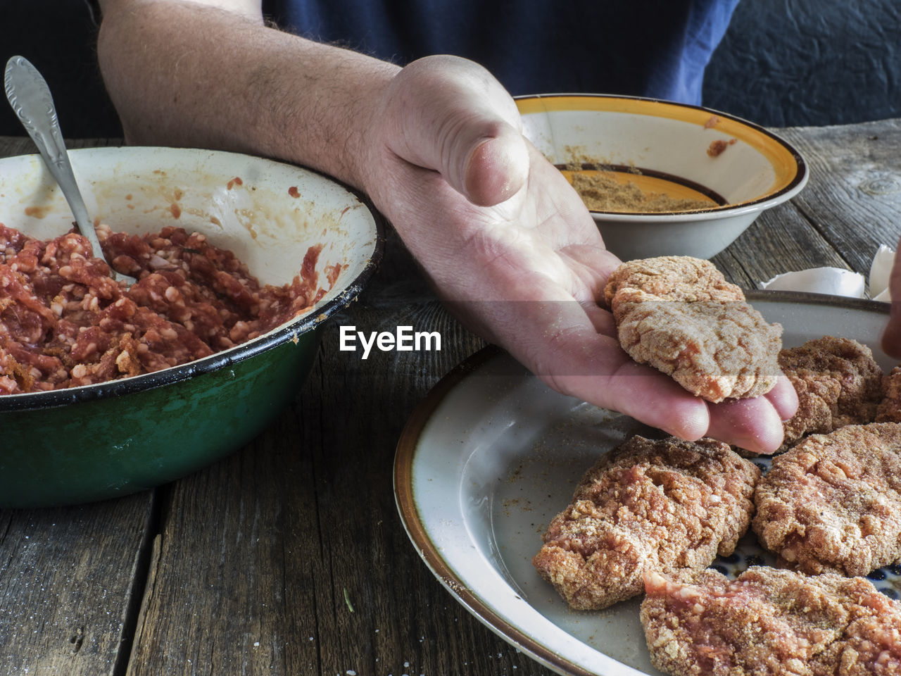 Cropped image of hands mixing batter by minced meat at table