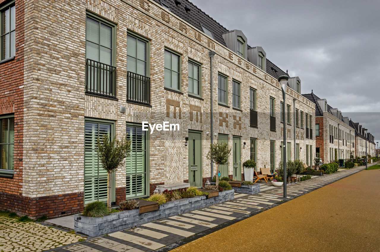 Street with row houses with brick facades decorated with text and the year mmxx, or 2020