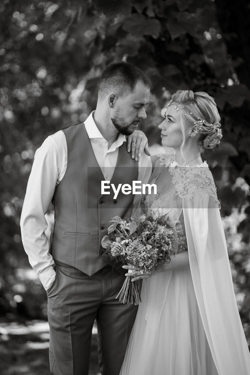 love, adult, women, wedding, positive emotion, two people, celebration, emotion, togetherness, event, bride, newlywed, married, men, female, wedding dress, life events, happiness, black and white, young adult, romance, formal wear, plant, standing, clothing, bouquet, flower arrangement, ceremony, flower, bonding, smiling, nature, person, affectionate, wedding ceremony, gown, fashion, elegance, dress, monochrome, monochrome photography, kissing, bridal clothing, outdoors, embracing, flowering plant, cheerful, three quarter length, day, tuxedo