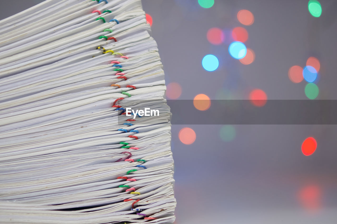 Close-up of paper stacked on table against blurred lights