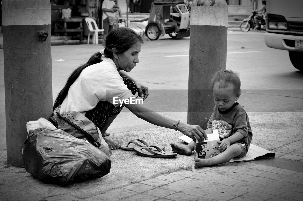 Mother with son sitting on street