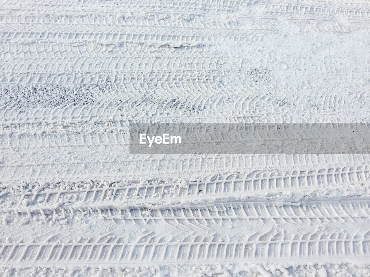 Full frame shot of tire tracks on snow covered field