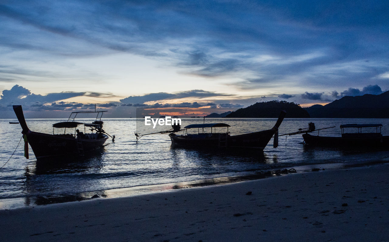 BOATS MOORED AT SEA SHORE AGAINST SKY