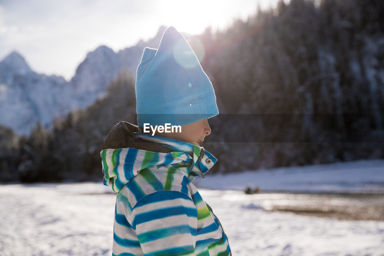 Boy with umbrella on snow covered land