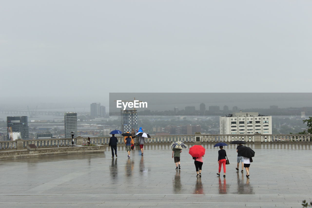 PEOPLE ON WET ROAD AGAINST SKY