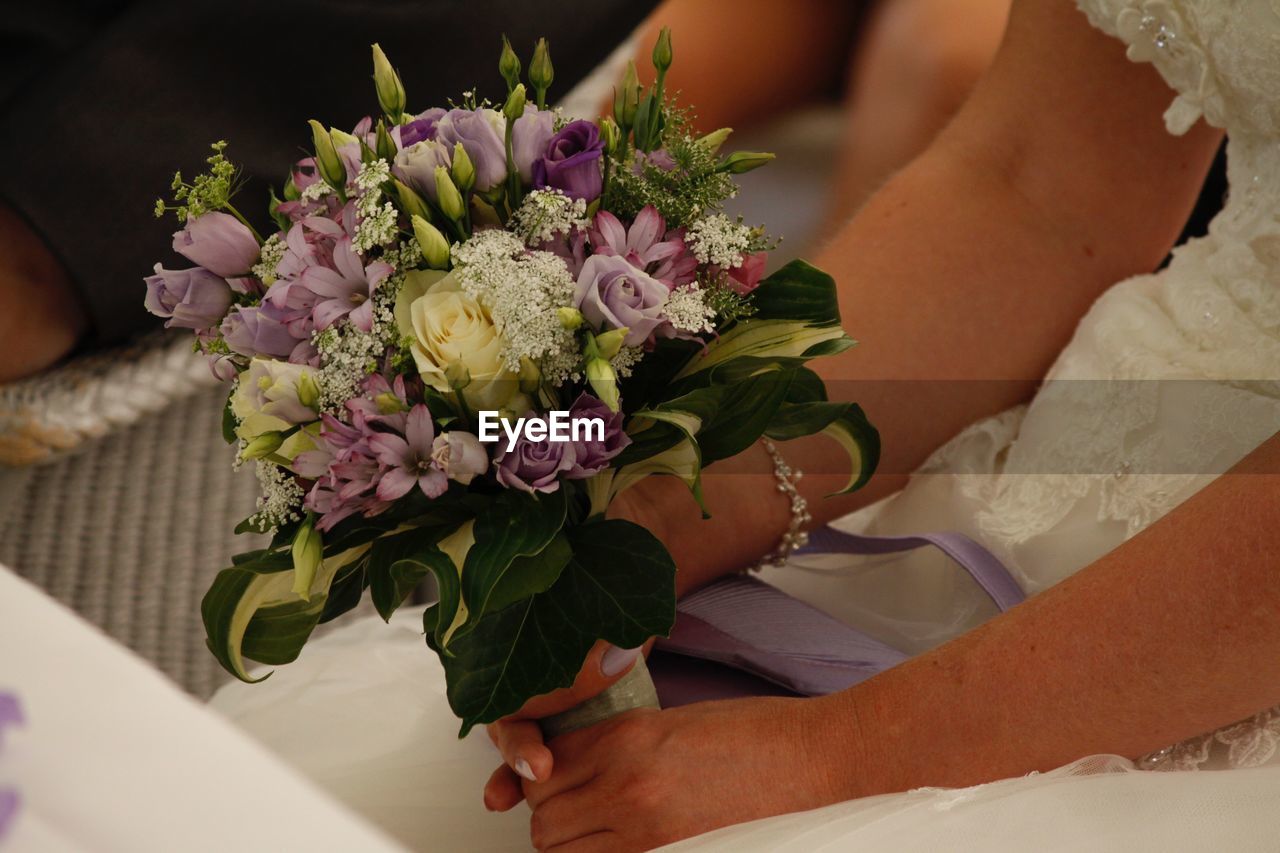 Midsection of bride holding bouquet