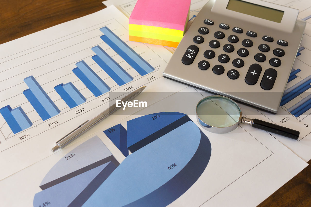 High angle view of calculator and office supply on financial chart