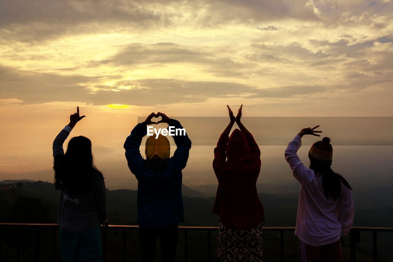 GROUP OF PEOPLE STANDING AT SUNSET