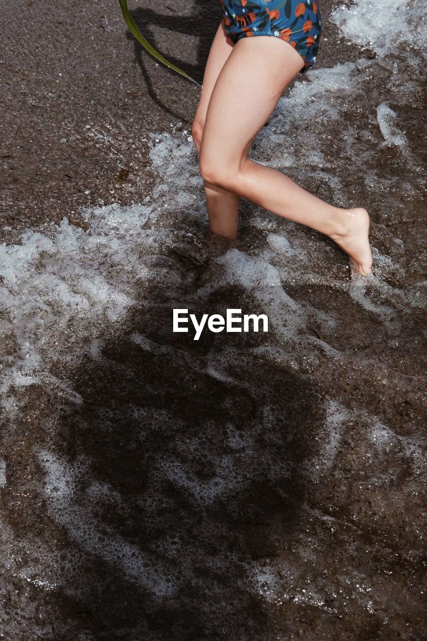 LOW SECTION OF WOMAN FEET IN WATER ON LAND