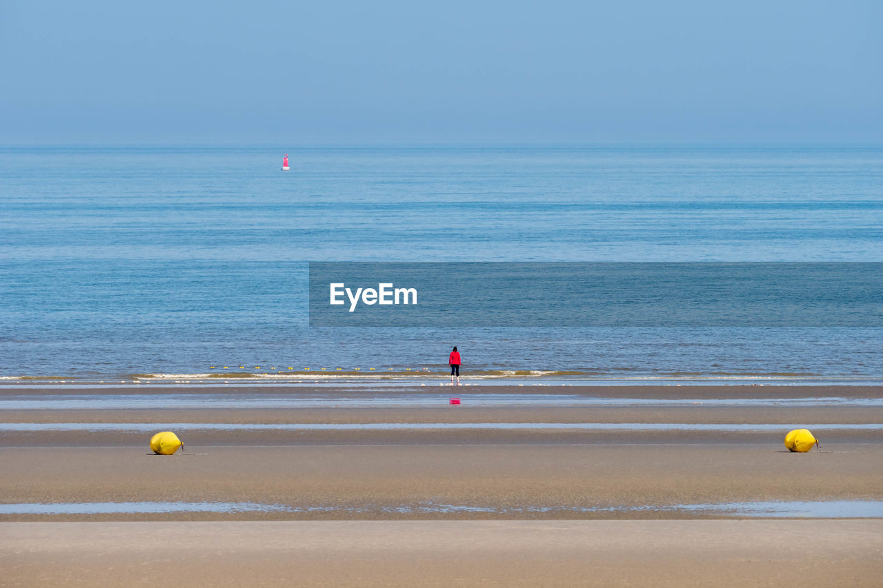 One woman in the distance enjoying an empty beach and the view across the sea at bray-dunes, france