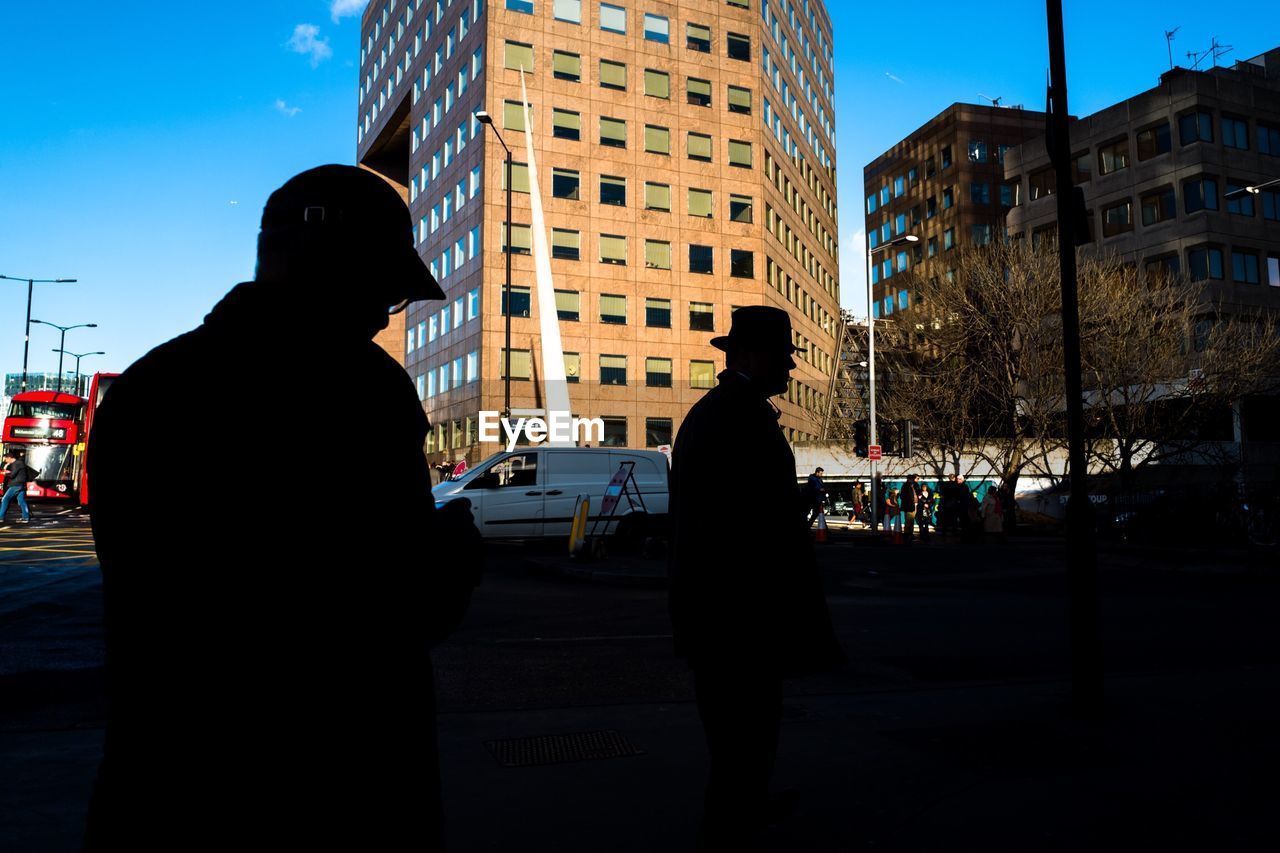 REAR VIEW OF SILHOUETTE WOMAN STANDING ON STREET