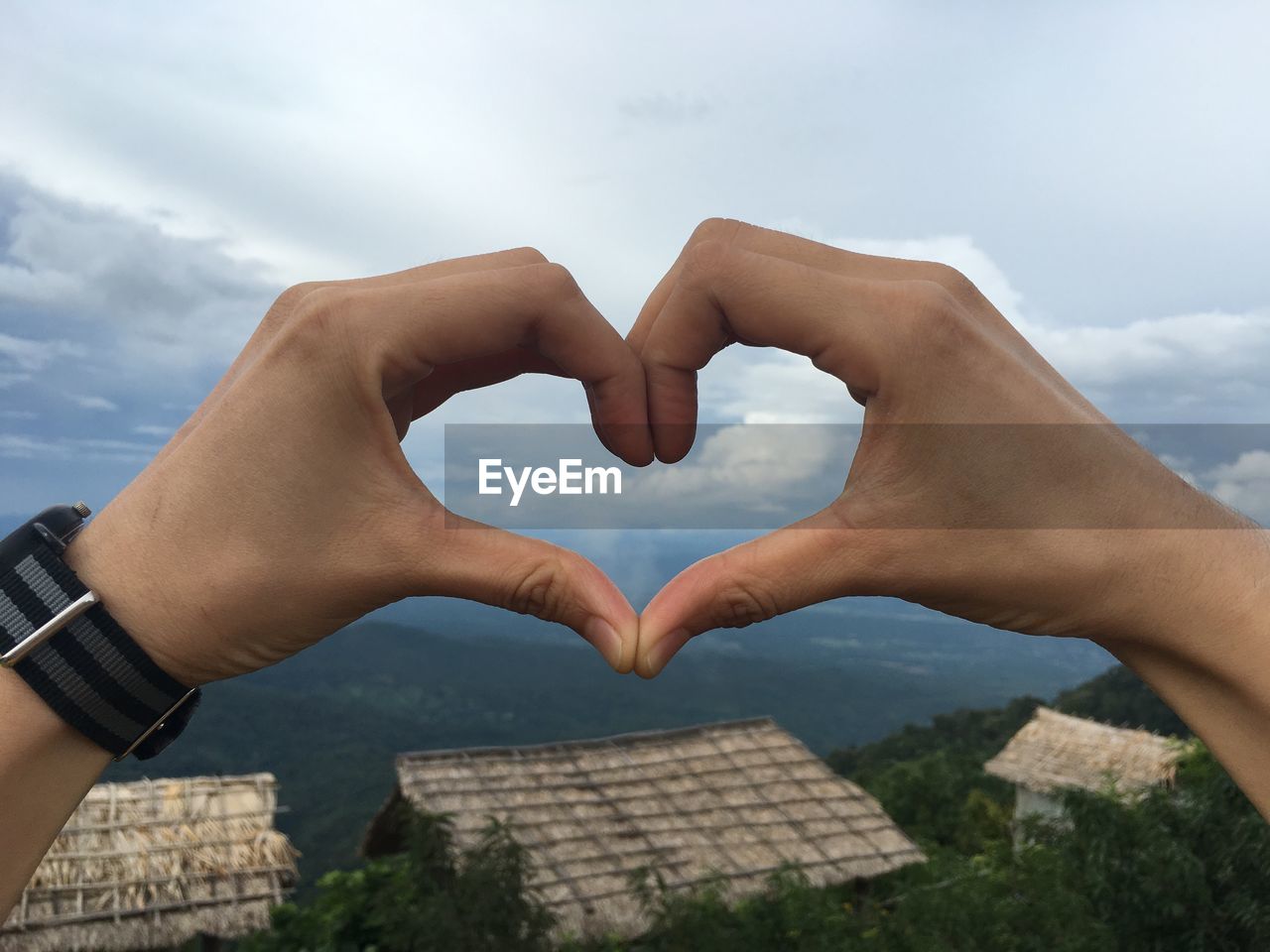 CLOSE-UP OF HEART SHAPE HANDS AGAINST SKY