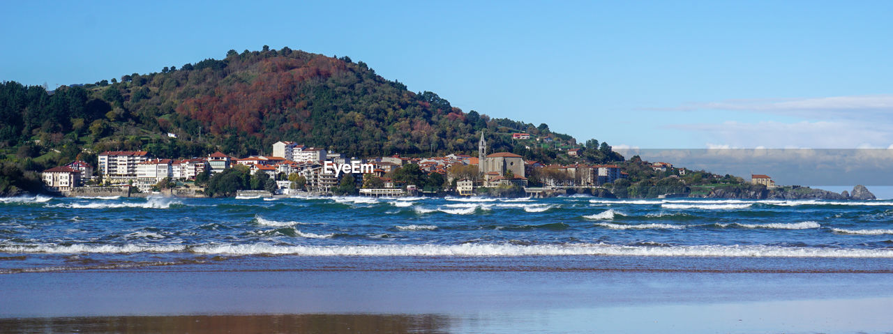 water, sea, land, beach, body of water, shore, sky, coast, nature, ocean, vacation, architecture, scenics - nature, bay, coastline, travel destinations, beauty in nature, building, building exterior, mountain, travel, no people, built structure, environment, wave, blue, house, day, outdoors, landscape, cove, sand, city, tourism, tranquility, tree, holiday, trip, rock, nautical vessel, clear sky, island, idyllic, tranquil scene, bay of water, sunny