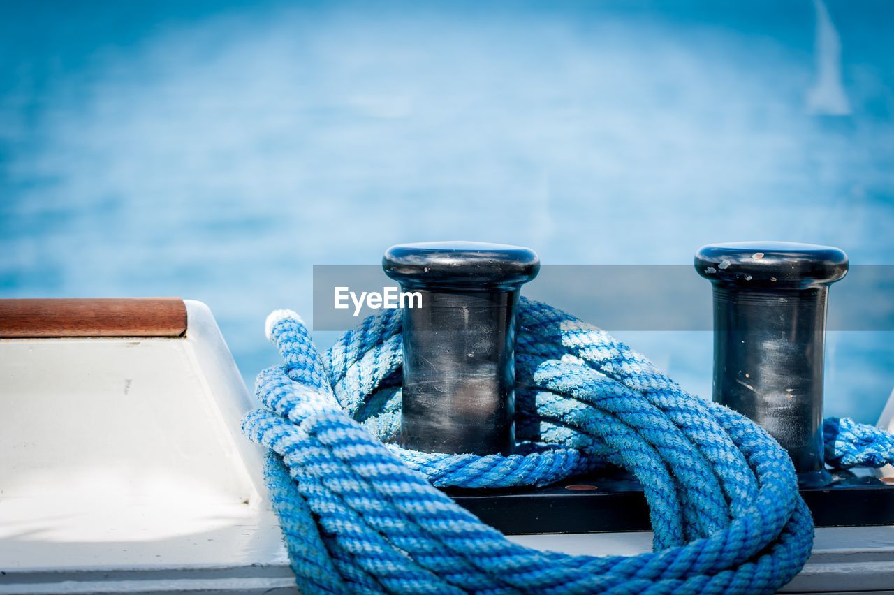 Close-up of rope tied to bollard by sea