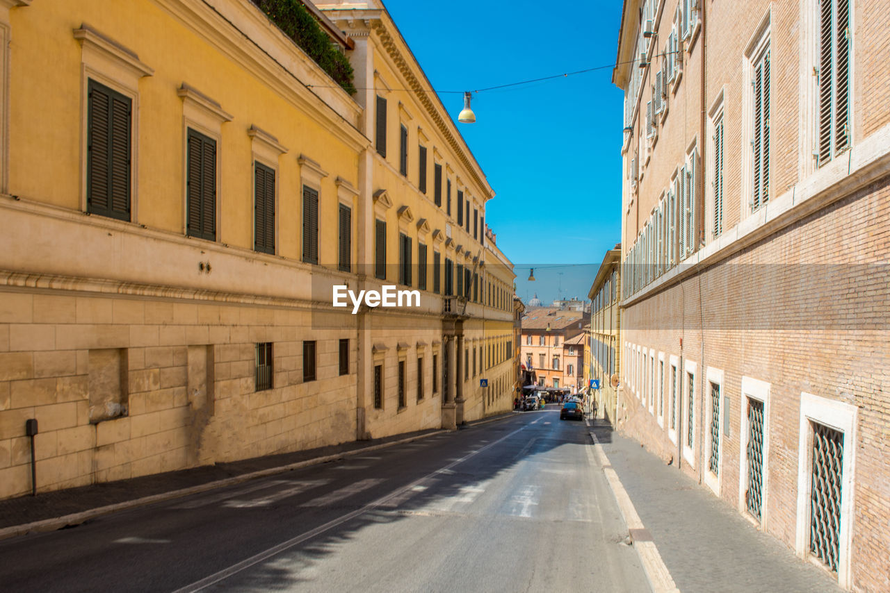 Road amidst buildings in city against clear sky