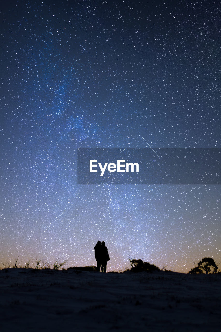 Silhouette person standing on field against sky at night