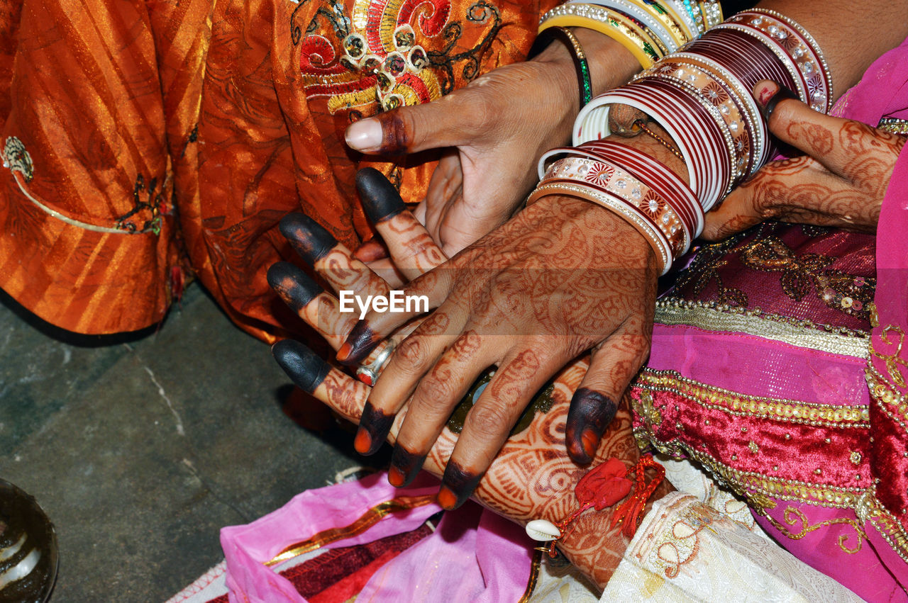 Bride and groom with henna painted hands completes hand matching ceremony in indian traditions.