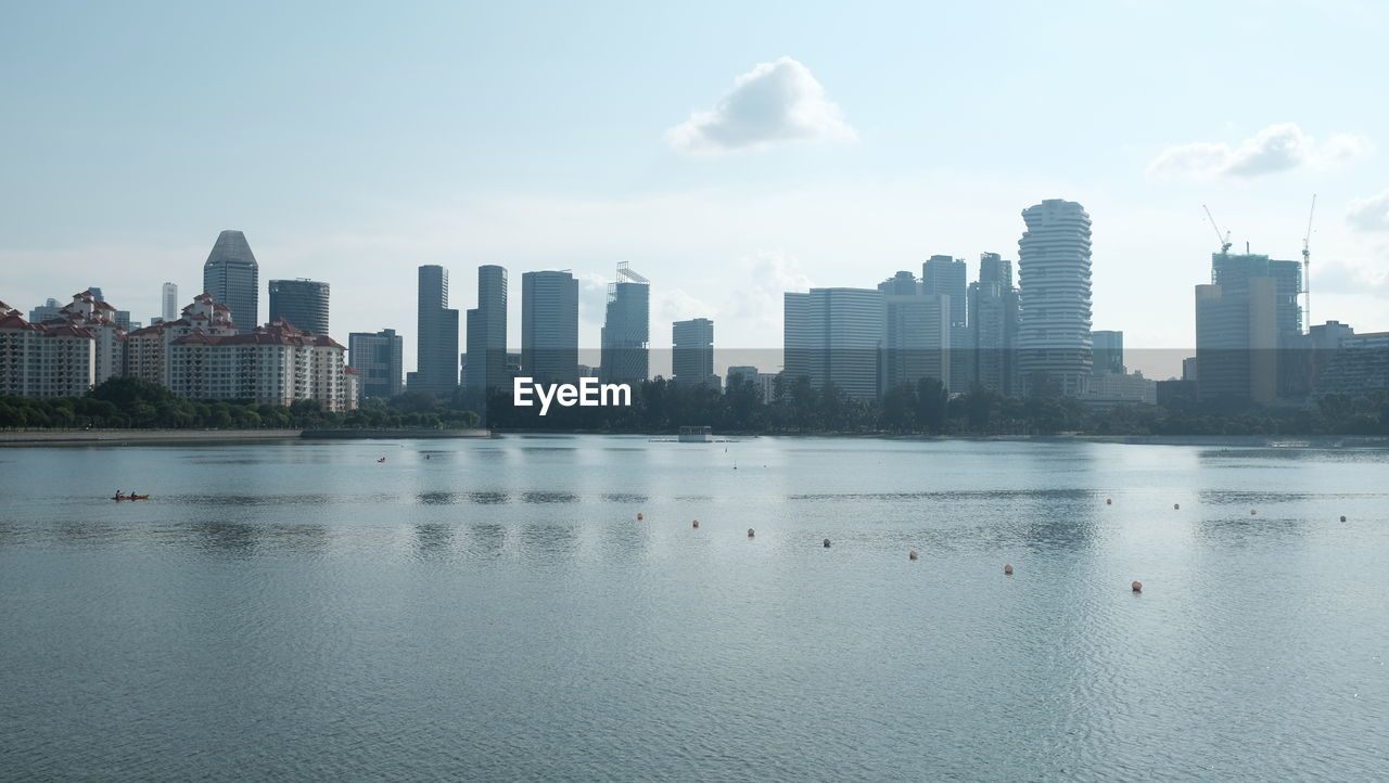 Sea and buildings in city against sky