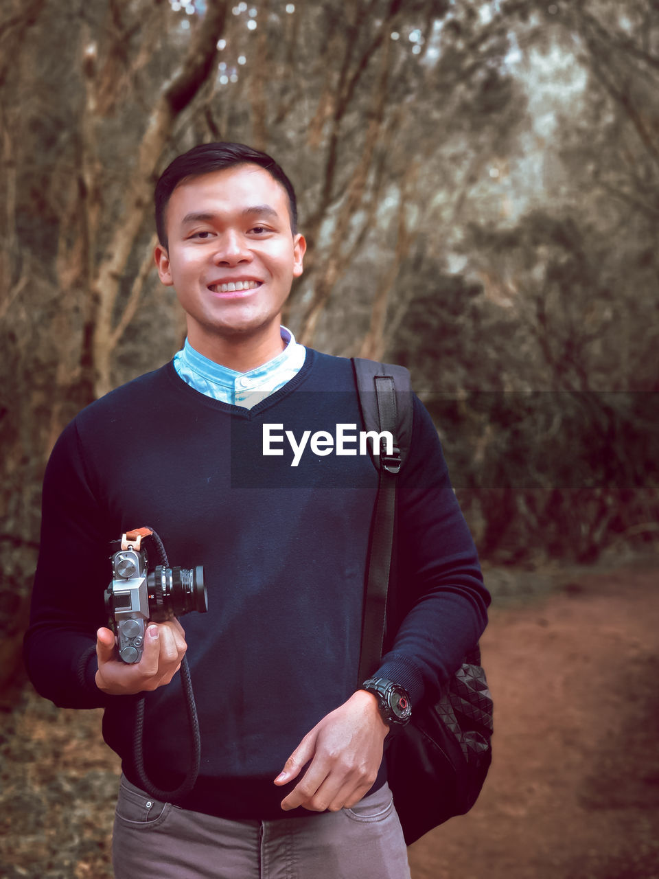 Young man holding camera with big smile on his face