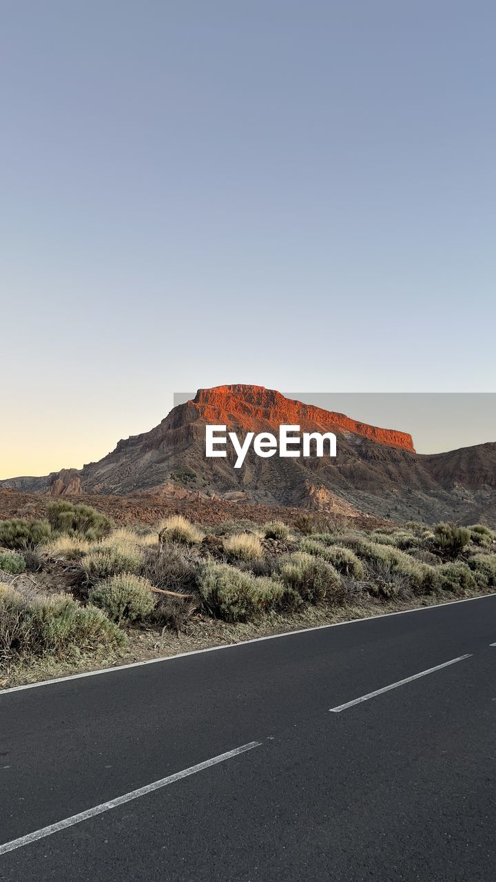 road leading towards mountains against clear sky