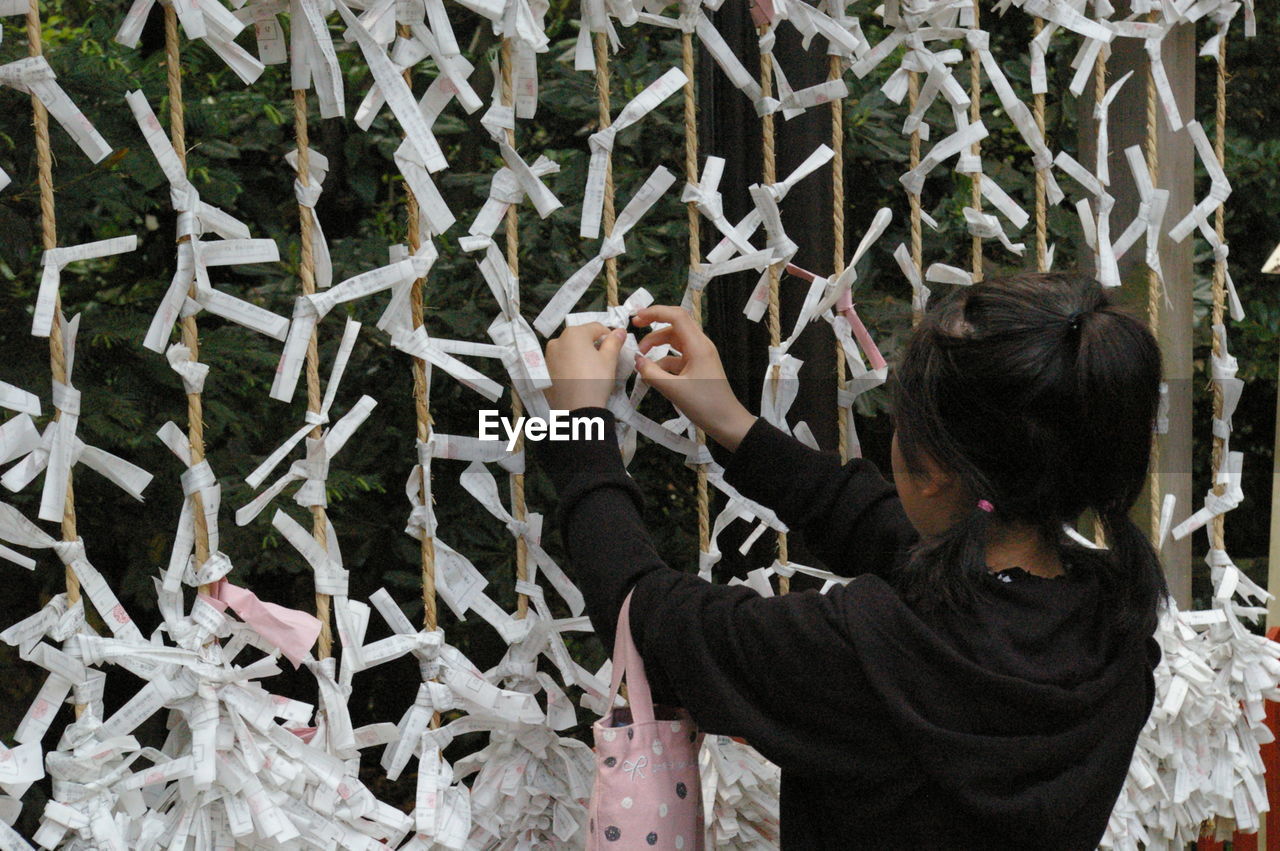 Girl tying paper on string