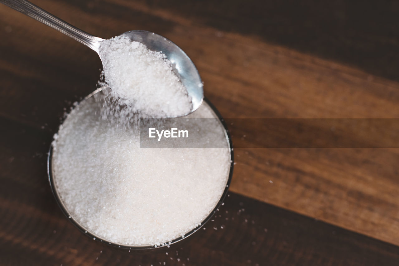 Sugar poured on a wooden table with diabetes word. concept of diabetes and unhealthy eating.