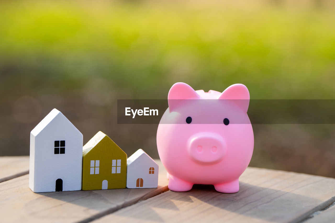 Wooden houses and piggy bank stands outdoors on a sunny day. real estate and investments 