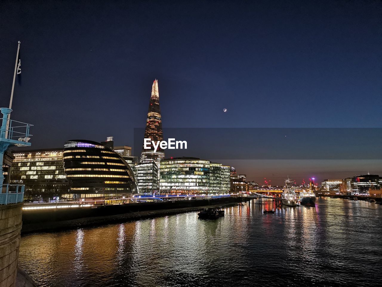 ILLUMINATED BUILDINGS IN CITY AT WATERFRONT