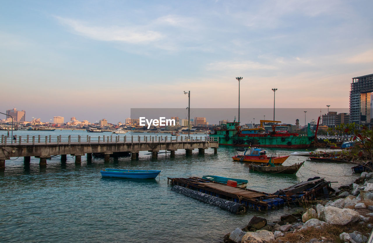 BOATS MOORED AT HARBOR DURING SUNSET