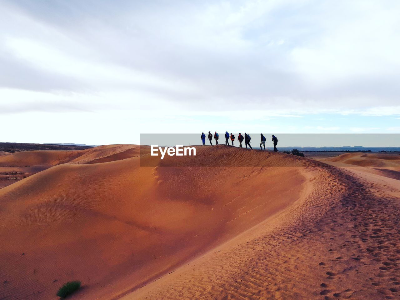 People on sand dune against sky