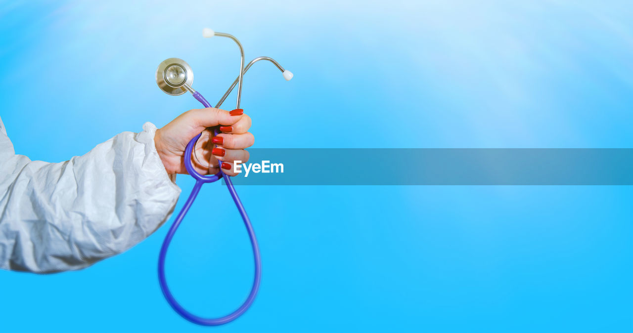 blue, one person, colored background, holding, blue background, adult, hand, copy space, stethoscope, healthcare and medicine, studio shot, occupation, indoors, medical instrument, young adult, expertise