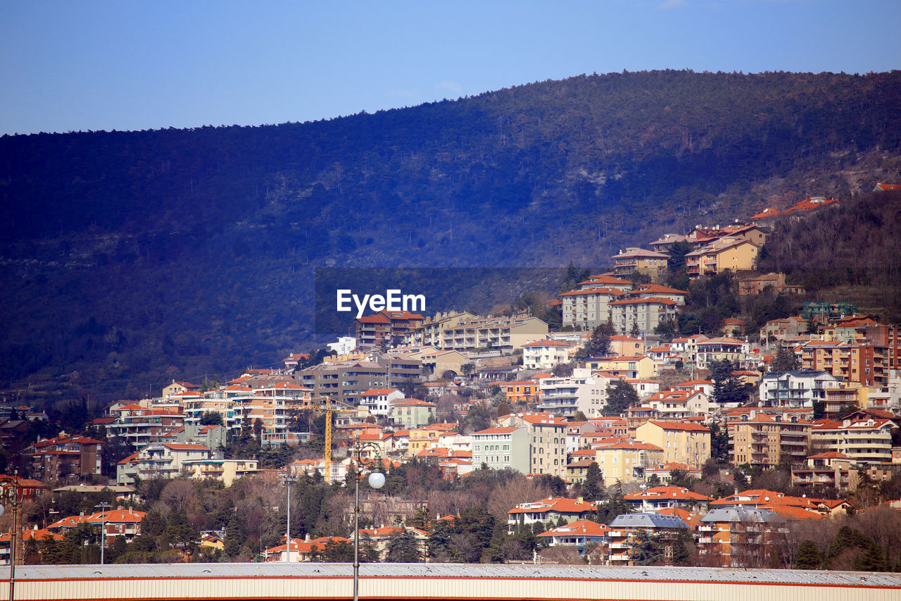 Townscape by mountains against clear sky