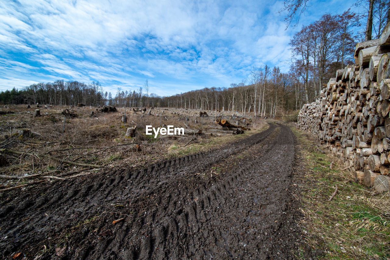 DIRT ROAD AMIDST LAND AGAINST SKY