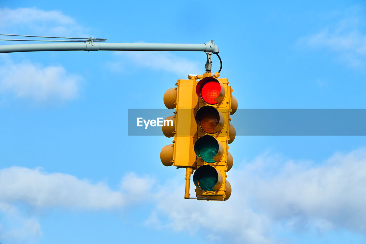 Close up of a yellow street traffic light hanging from a pole