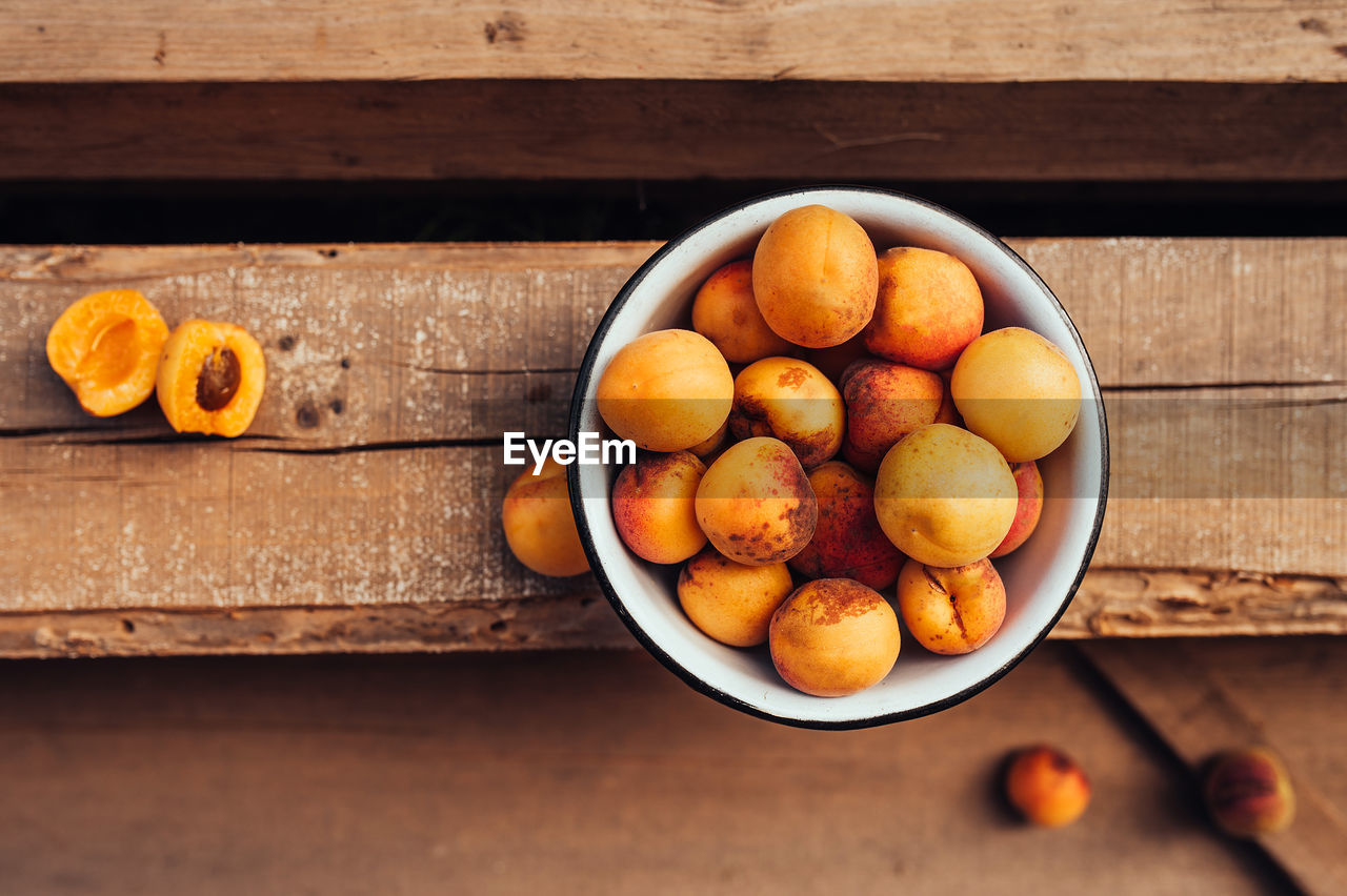 Ripe juicy homemade apricots with cracks and flaws in the plate and scattered on wooden boards