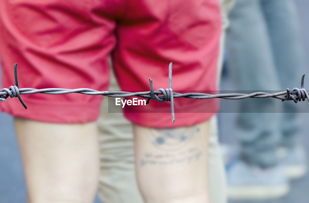 Close-up of man's midsection behind barbed wire