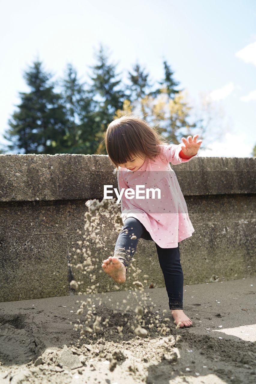 View of young girl kicking sand