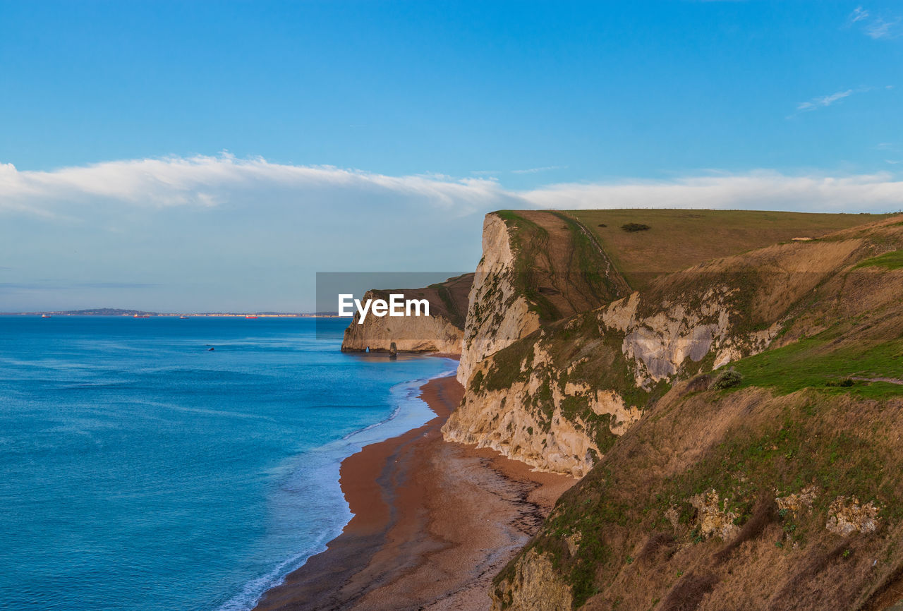 Scenic view of cliffs nu the sea against sky