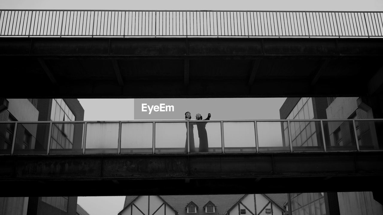 LOW ANGLE VIEW OF MAN ON BRIDGE AGAINST SKY