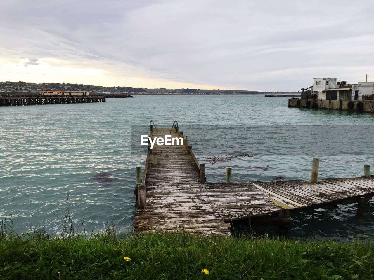 Pier amidst lake against cloudy sky